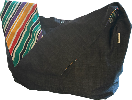 Front view of Nomad Stitchez Black Denim Sling Bag with bold bias-cut stripe in primary colors.