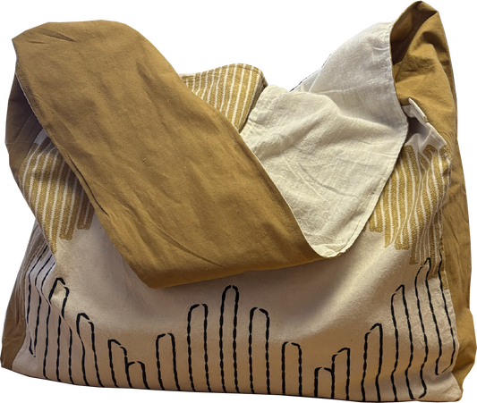 Mustard and black printed sling bag with a solid mustard yellow strap and natural cotton muslin lining.