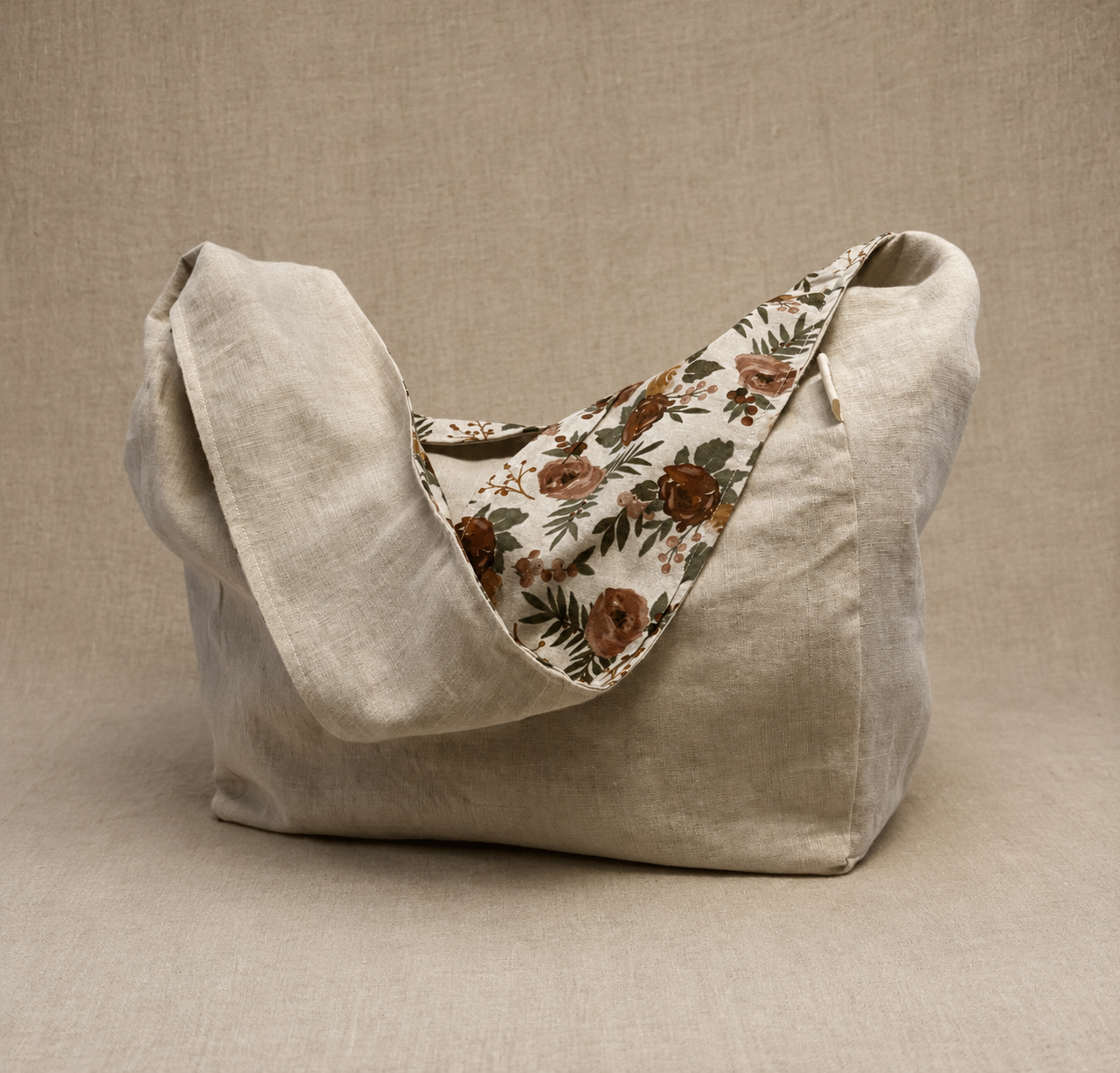 Front view of the Evergreen Rose 1/2-Pint Stitch Bag featuring a soft floral print with rust, blush, and evergreen tones on a natural linen-look fabric with structured front pocket detailing.