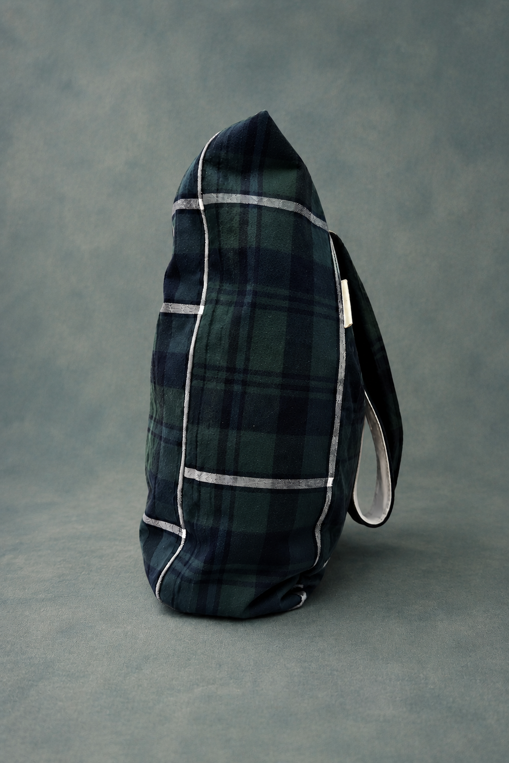 Side view of the Half-Pint Stitch Bag featuring a navy plaid cotton shell, soft slouchy silhouette, and handcrafted construction with a clean structured base.