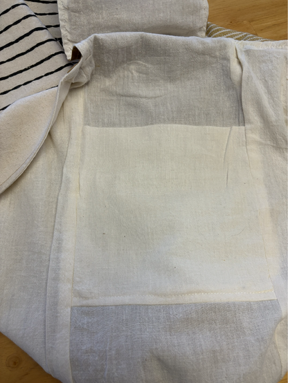 Interior of the sling bag displaying natural cotton muslin lining and built-in strap pockets.