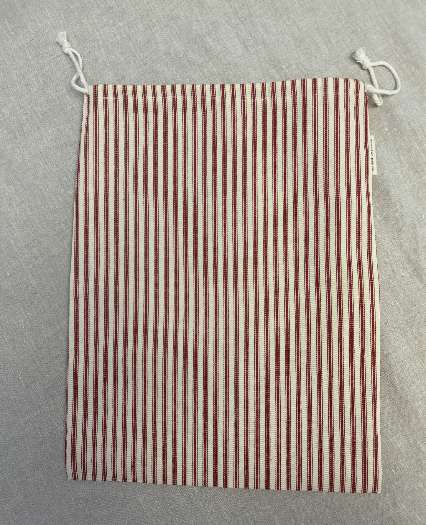 Vertical red stripe cotton utility bag with a cotton drawstring closure, 12in x 15in size, part of the Essentials Collection.