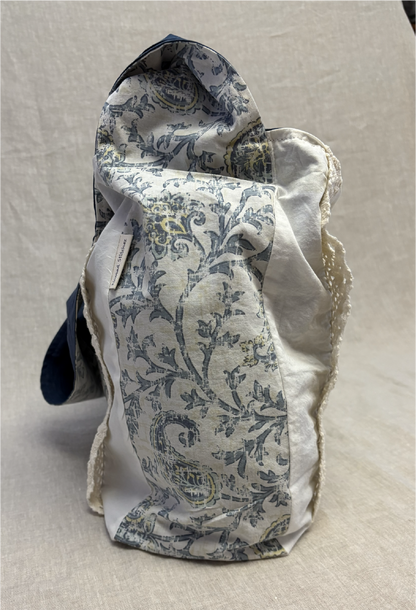 Side view of the blue boho chic floral ½ pint stitch bag showing its slim profile and floral fabric, with the cotton lace accent slightly visible from this angle.