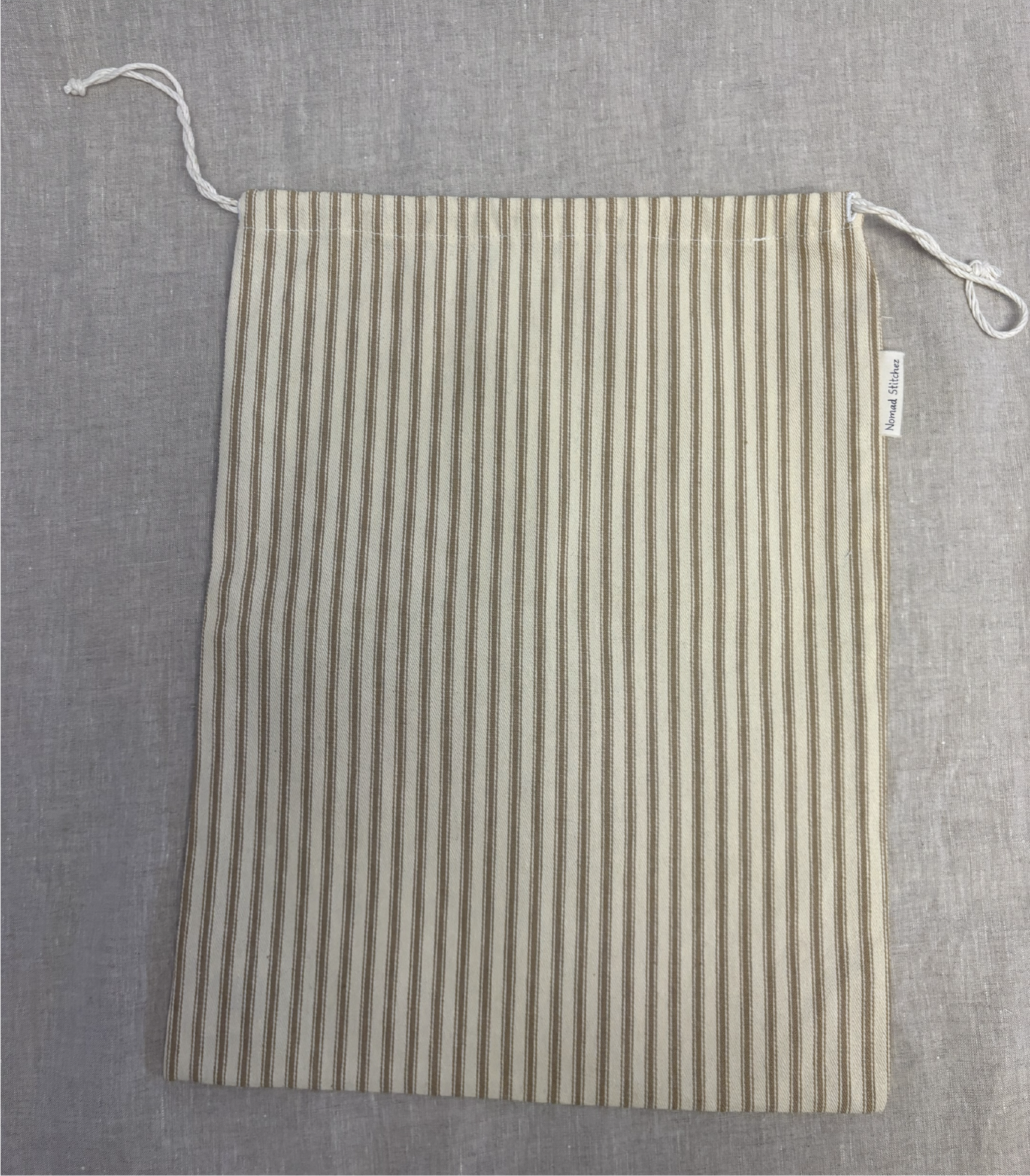 Vertical tan stripe cotton utility bag with a cotton drawstring closure, 12in x 15in size, part of the Essentials Collection.