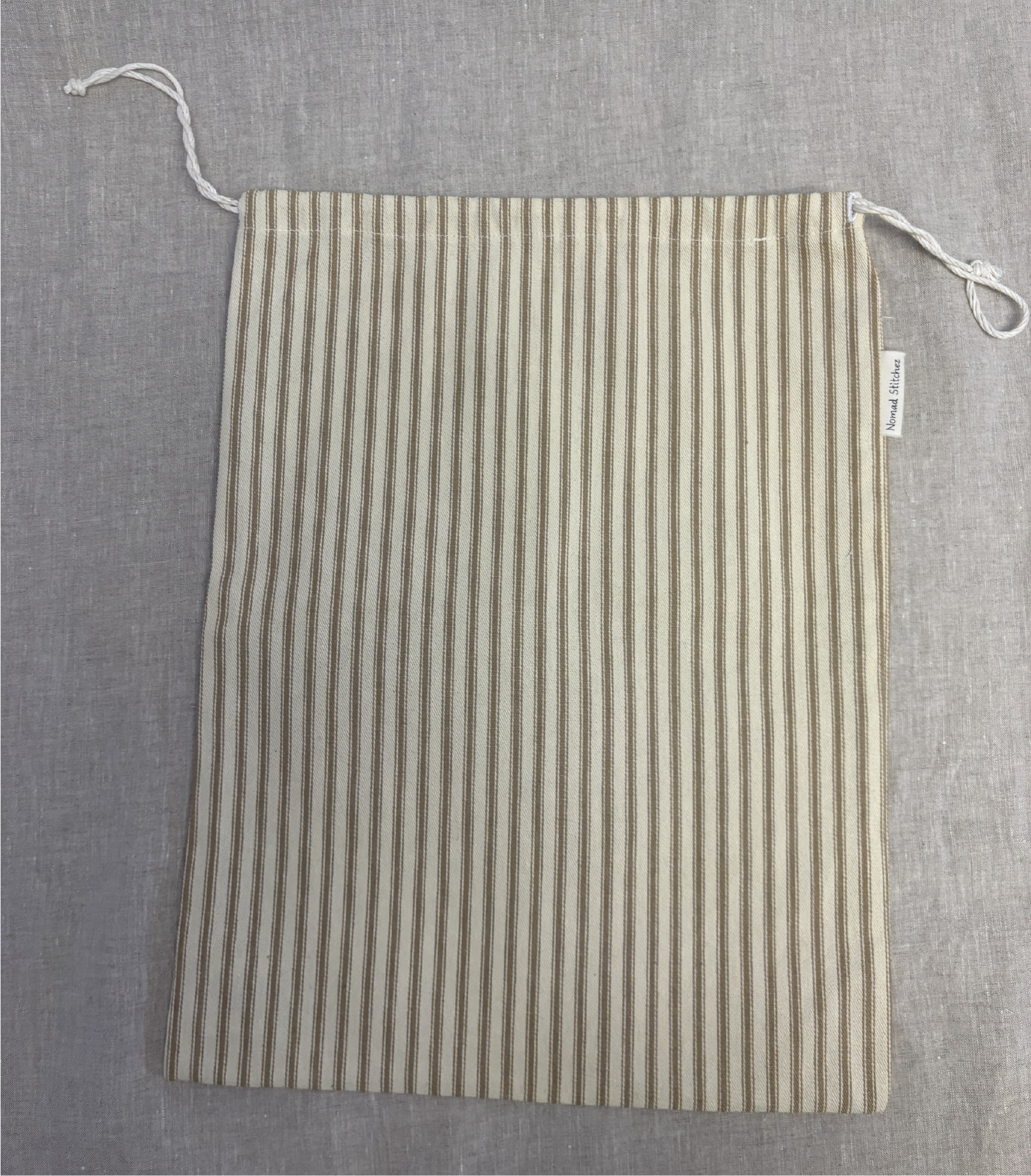 Vertical tan stripe cotton utility bag with a cotton drawstring closure, 12in x 15in size, part of the Essentials Collection.