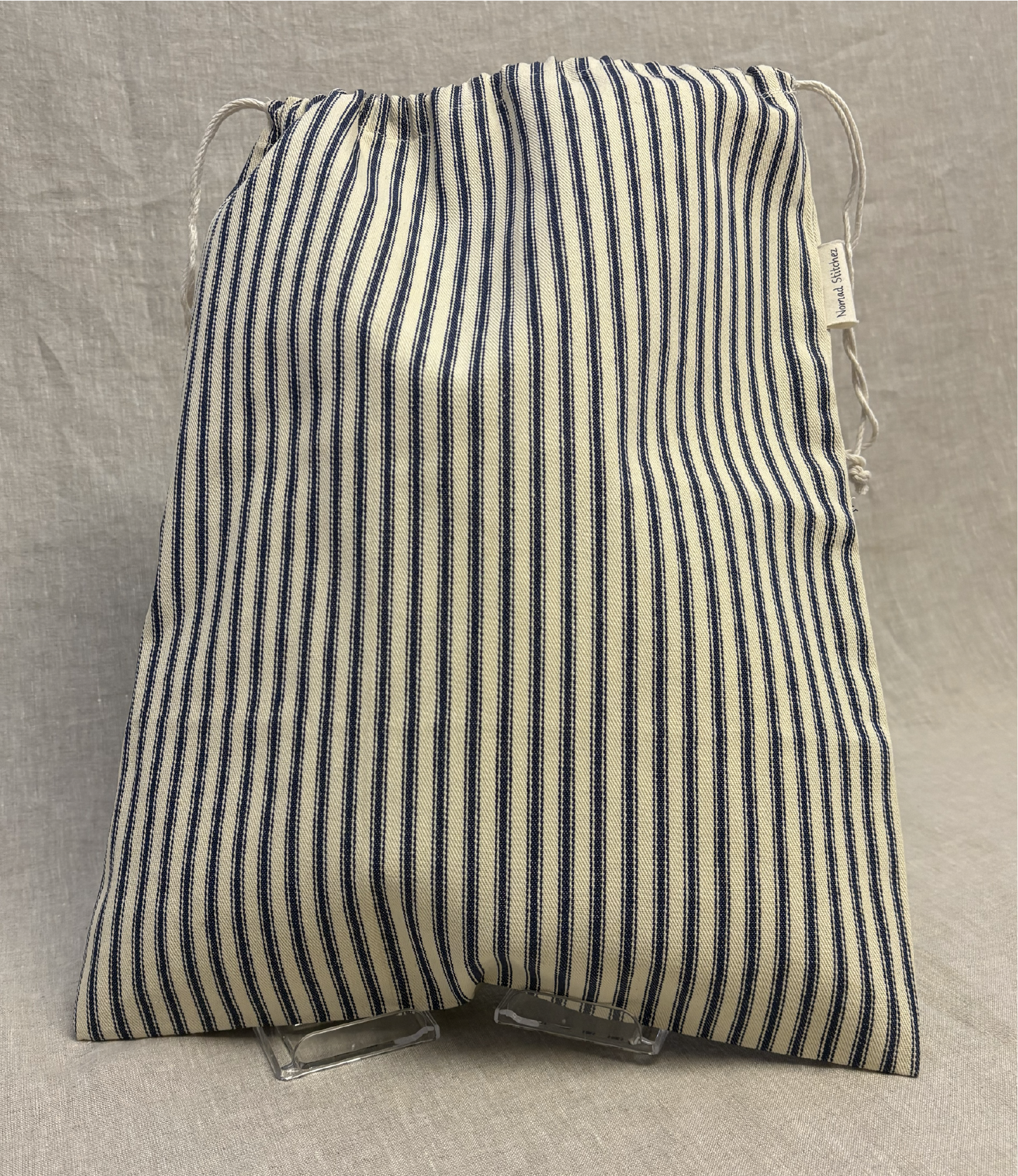 Vertical blue stripe cotton utility bag with a cotton drawstring closure, 12in x 15in size, part of the Essentials Collection.
